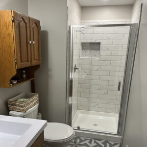 New subfloor, tile floor and in shower, new vanity, toilet and shower door. (After)